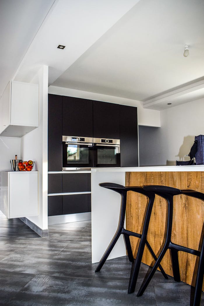 journey-02 A contemporary kitchen featuring sleek cabinetry and elegant bar stools in a minimalist design.